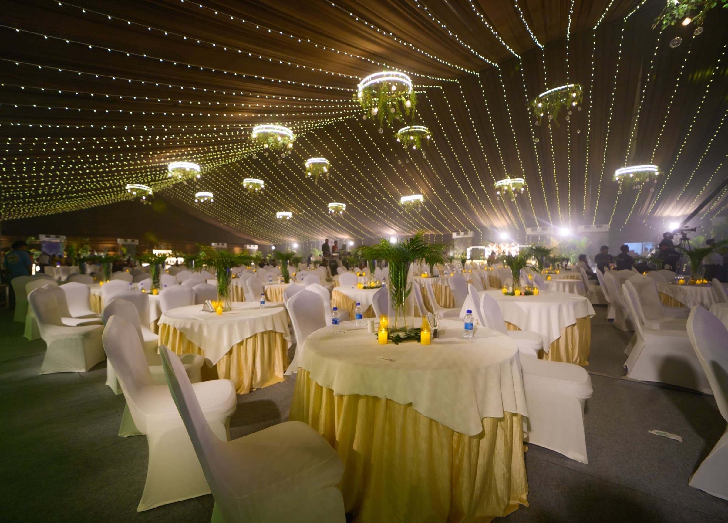 Product launch reception dining tables styled with gold linens and string lights