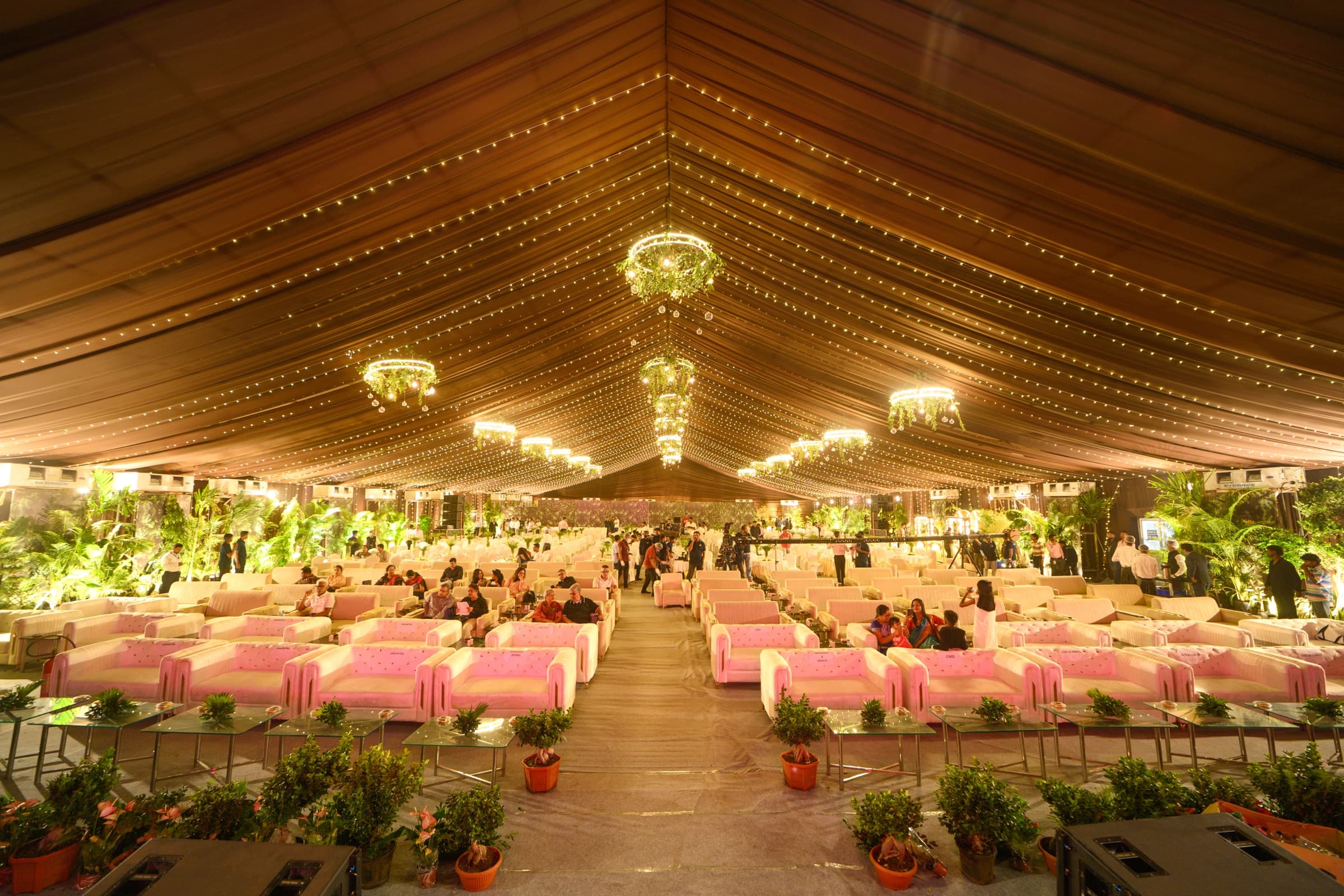 Elegant lounge seating under string lights and floral chandeliers at an evening reception