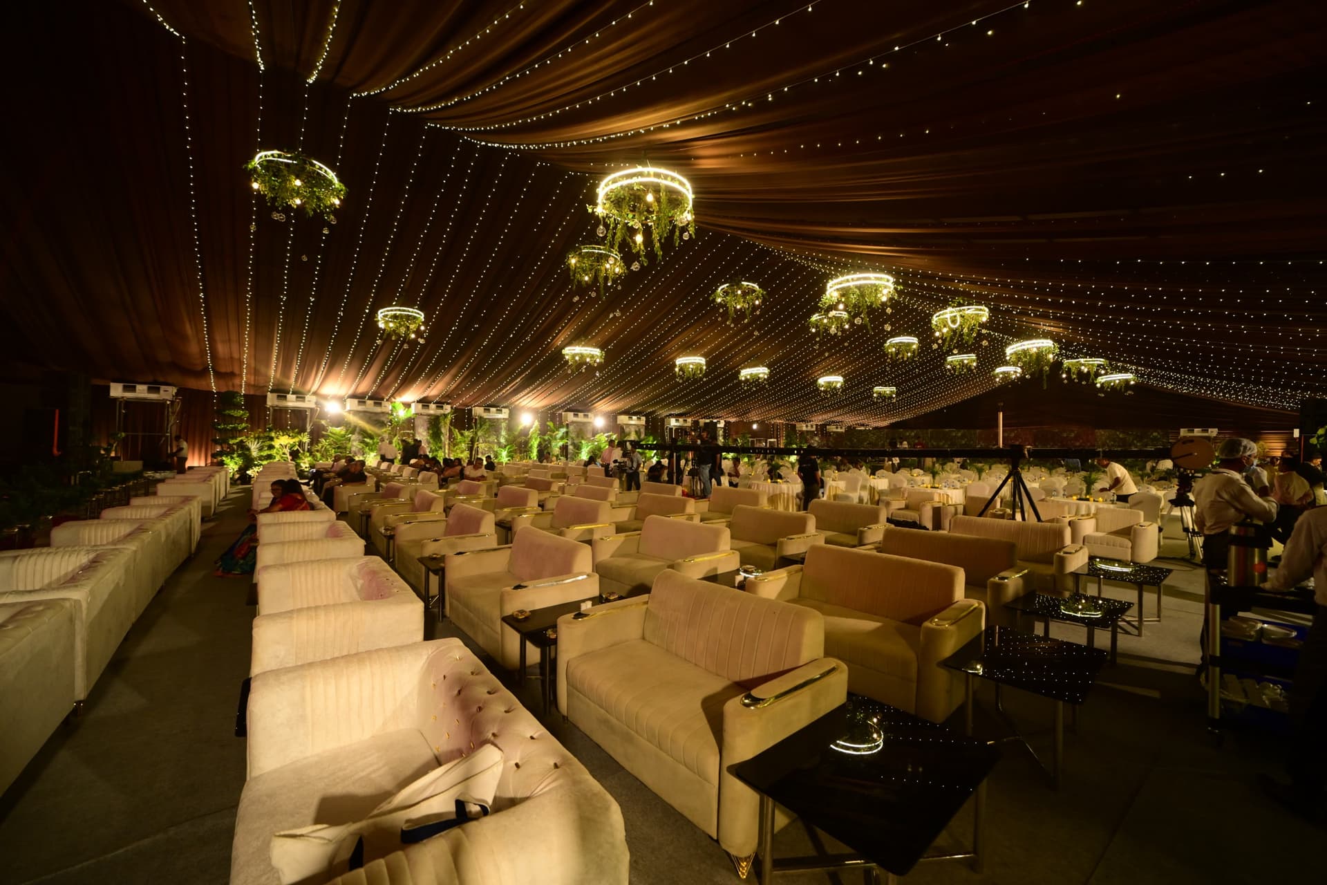 Lounge seating styled with floral chandeliers and string lights
