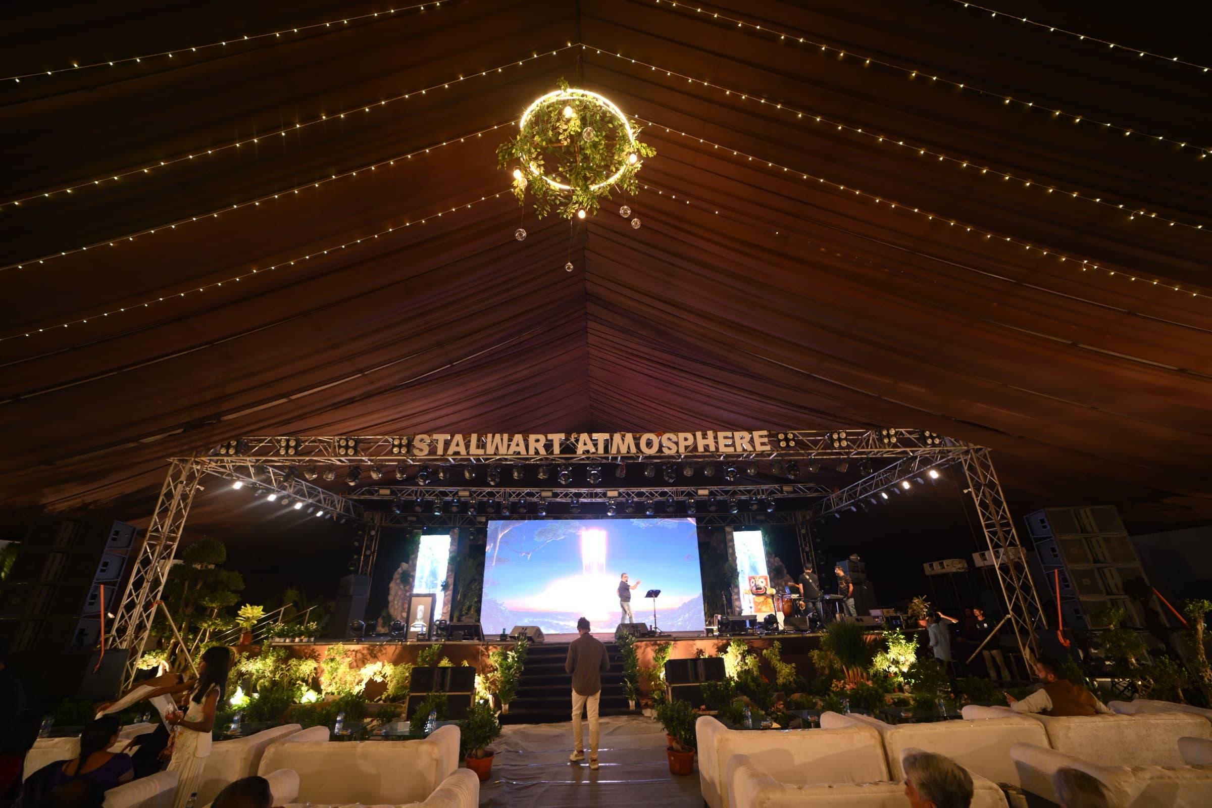Large-scale event stage with screen and lounge seating for guests